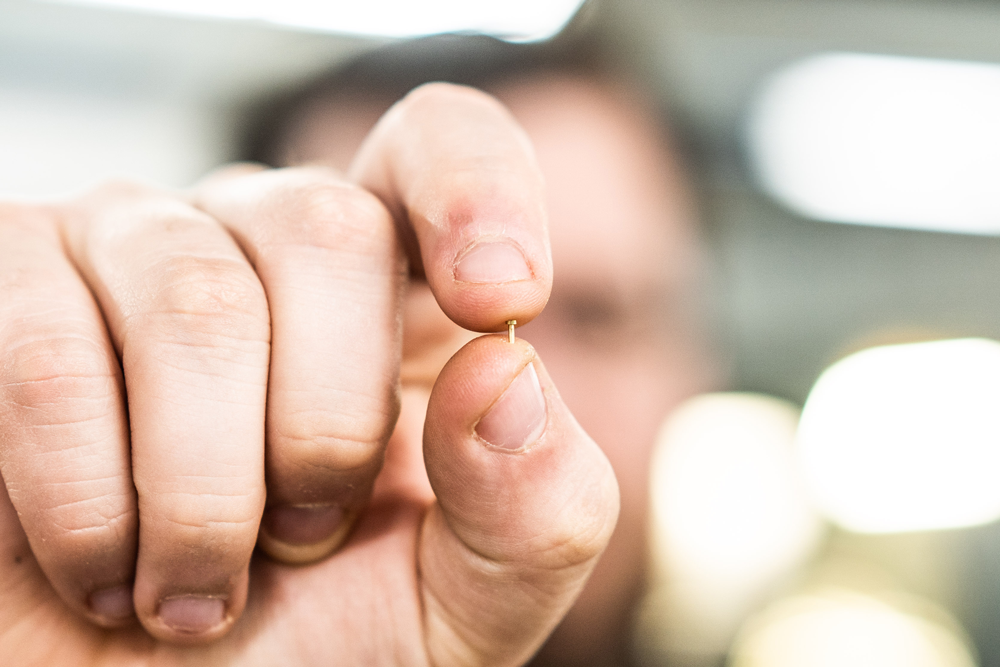 person holding micro machined fastener screw
